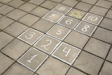 Hopscotch drawn with white chalk on street tiles outdoors