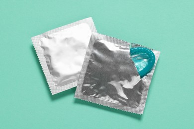 Photo of Condoms on turquoise background, top view. Safe sex