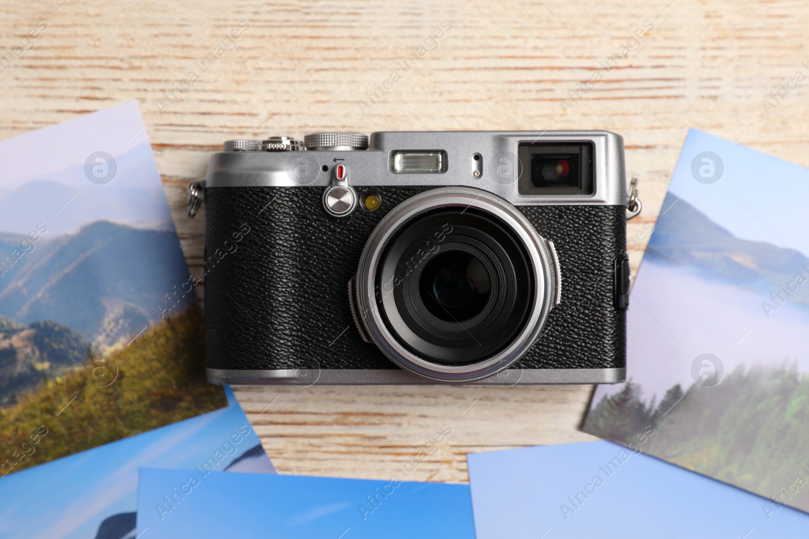 Photo of Vintage photo camera and beautiful printed pictures on wooden table, flat lay. Creative hobby