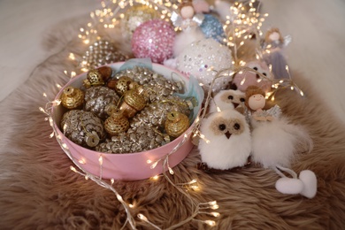 Photo of Beautiful Christmas tree baubles, toys and fairy lights on faux fur