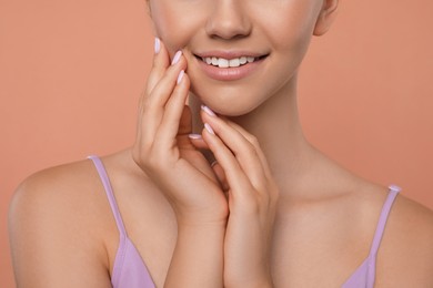Photo of Girl on pale coral background, closeup. Beautiful face with perfect smooth skin