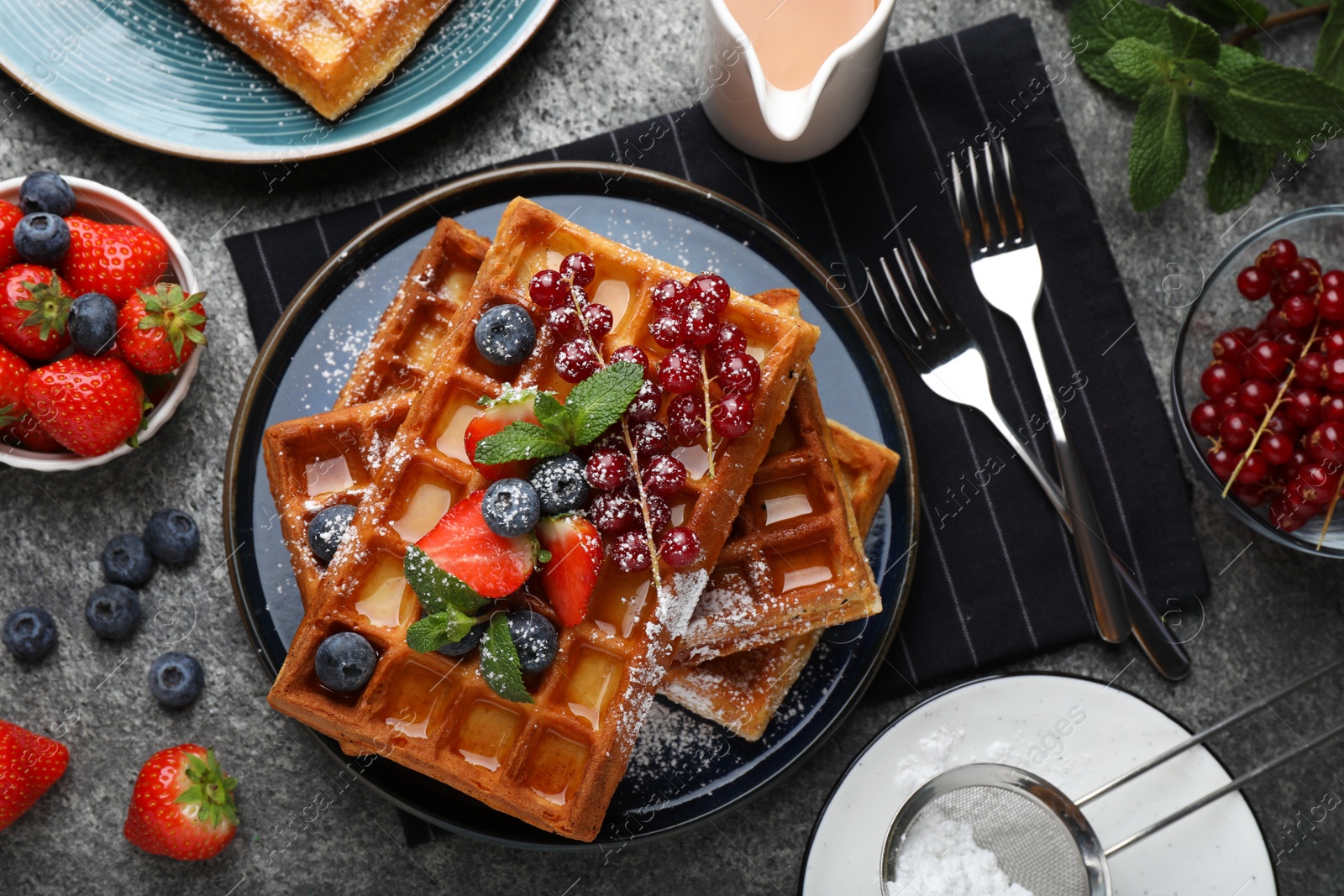 Photo of Delicious Belgian waffles with berries served on grey table, flat lay