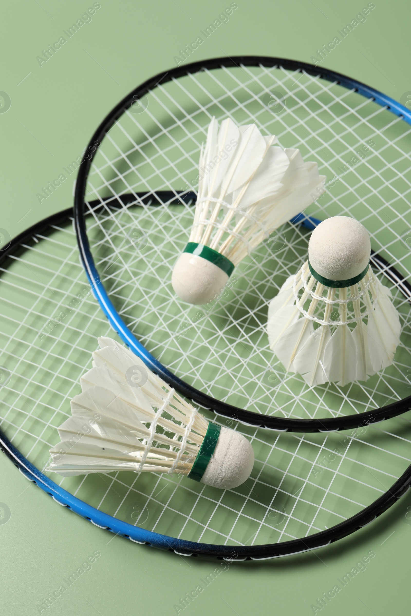 Photo of Feather badminton shuttlecocks and rackets on green background, above view