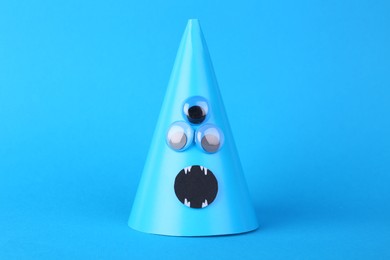 Photo of Spooky paper monster on light blue background. Handmade Halloween decoration