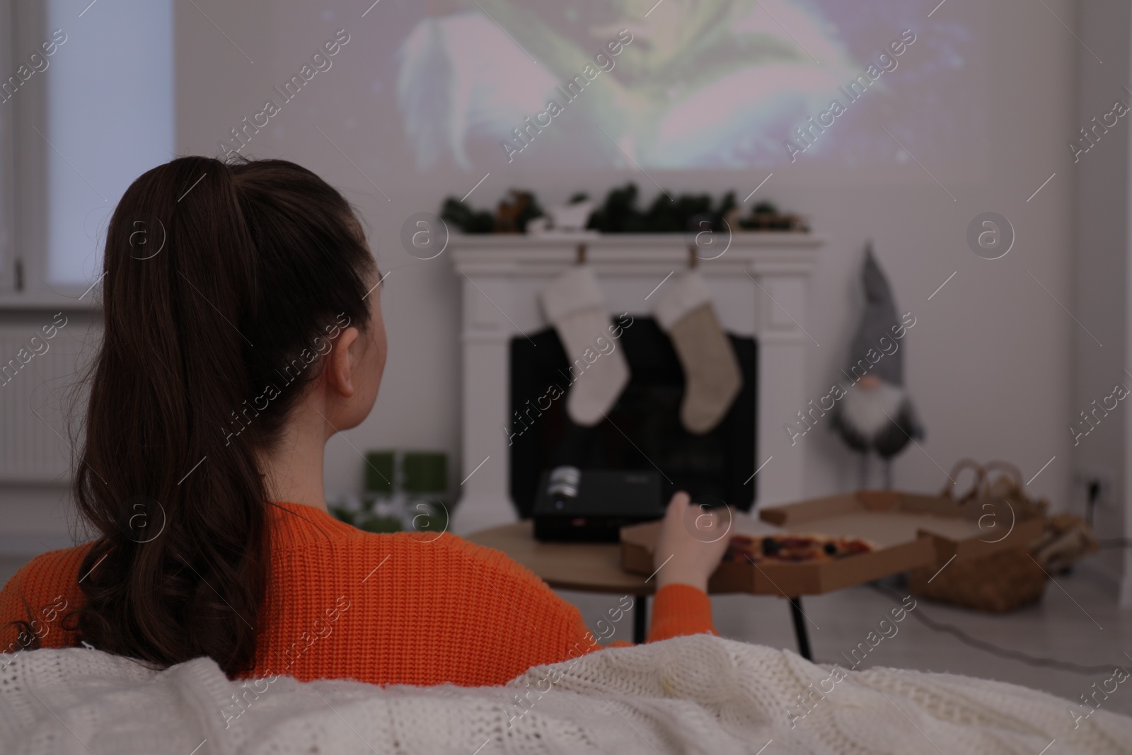 Photo of Lviv, Ukraine – January 24, 2023: Woman watching How the Grinch Stole Christmas movie via video projector at home, back view