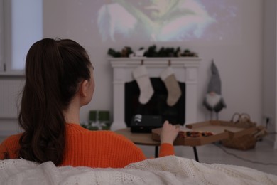Lviv, Ukraine – January 24, 2023: Woman watching How the Grinch Stole Christmas movie via video projector at home, back view
