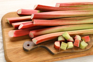 Many cut rhubarb stalks on white wooden table, closeup