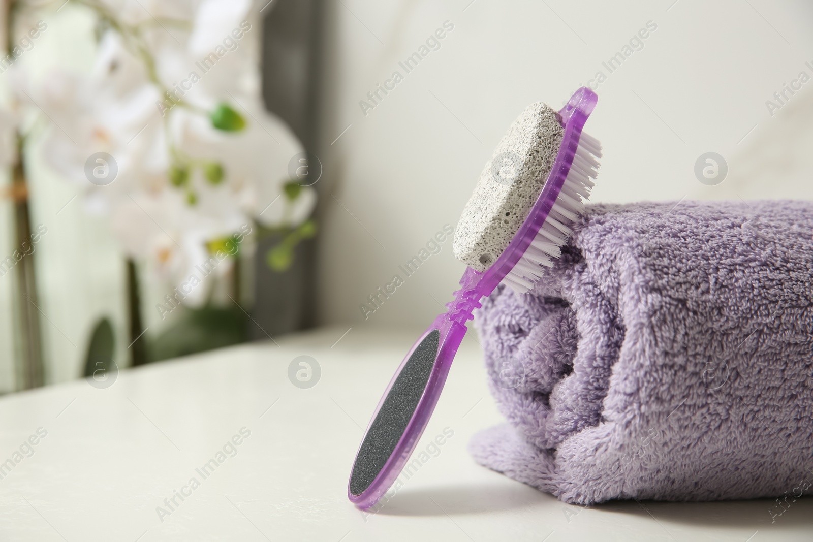Photo of Pedicure tool with pumice stone and foot file near towel on white table, closeup. Space for text