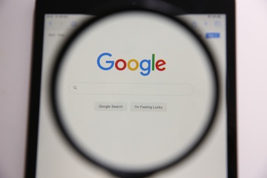 Photo of MYKOLAIV, UKRAINE - OCTOBER 30, 2020: Looking through magnifying glass at screen with Google search bar on white background