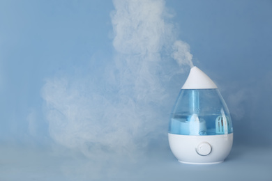 Photo of Modern air humidifier on light blue background. Space for text