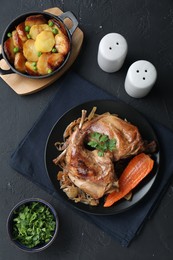 Photo of Tasty cooked rabbit meat with vegetables and potato served on black table, flat lay