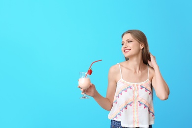 Young woman with glass of delicious milk shake on color background