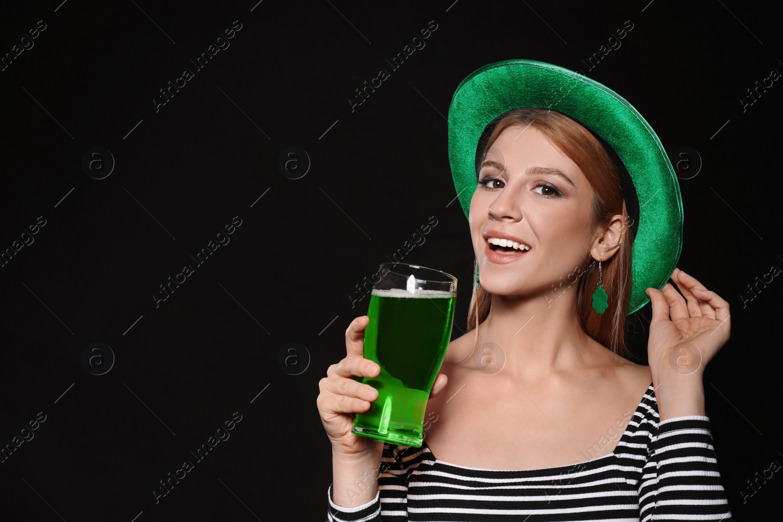 Photo of Young woman with green beer on black background. St. Patrick's Day celebration