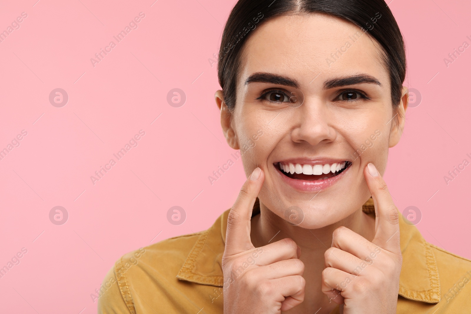 Photo of Woman showing her clean teeth and smiling on pink background, space for text