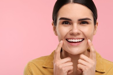 Woman showing her clean teeth and smiling on pink background, space for text