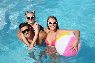 Photo of Happy family with inflatable ball in outdoor swimming pool on sunny summer day