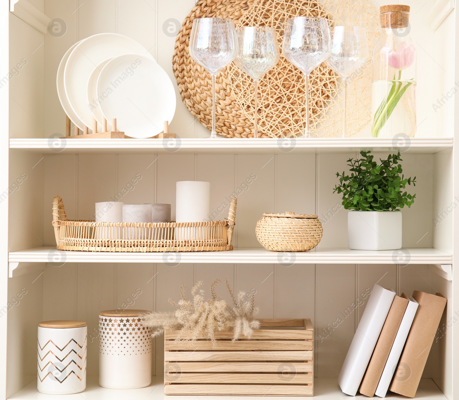 Photo of White shelving unit with dishware and different decorative stuff