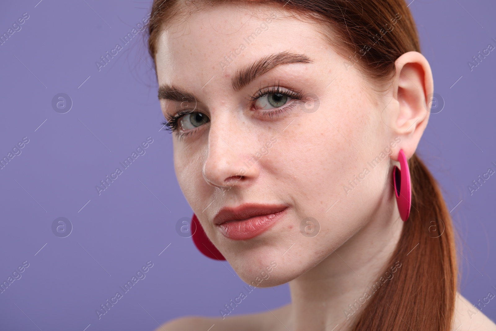 Photo of Portrait of beautiful woman with freckles on purple background, closeup