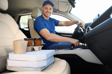 Photo of Male courier with orders in car. Food delivery service