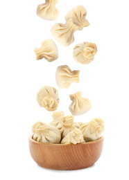 Image of Many tasty dumplings falling into wooden bowl on white background