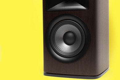 Photo of One wooden sound speaker on yellow background, closeup. Space for text