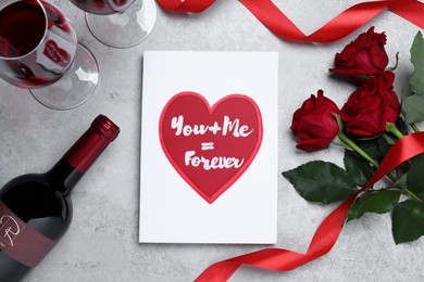 Card with romantic message, wine and red roses on grey table, flat lay. Love confession