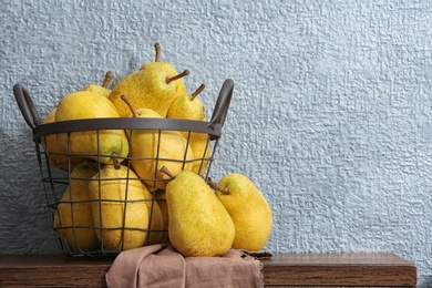 Photo of Basket of fresh ripe pears on table against color background with space for text