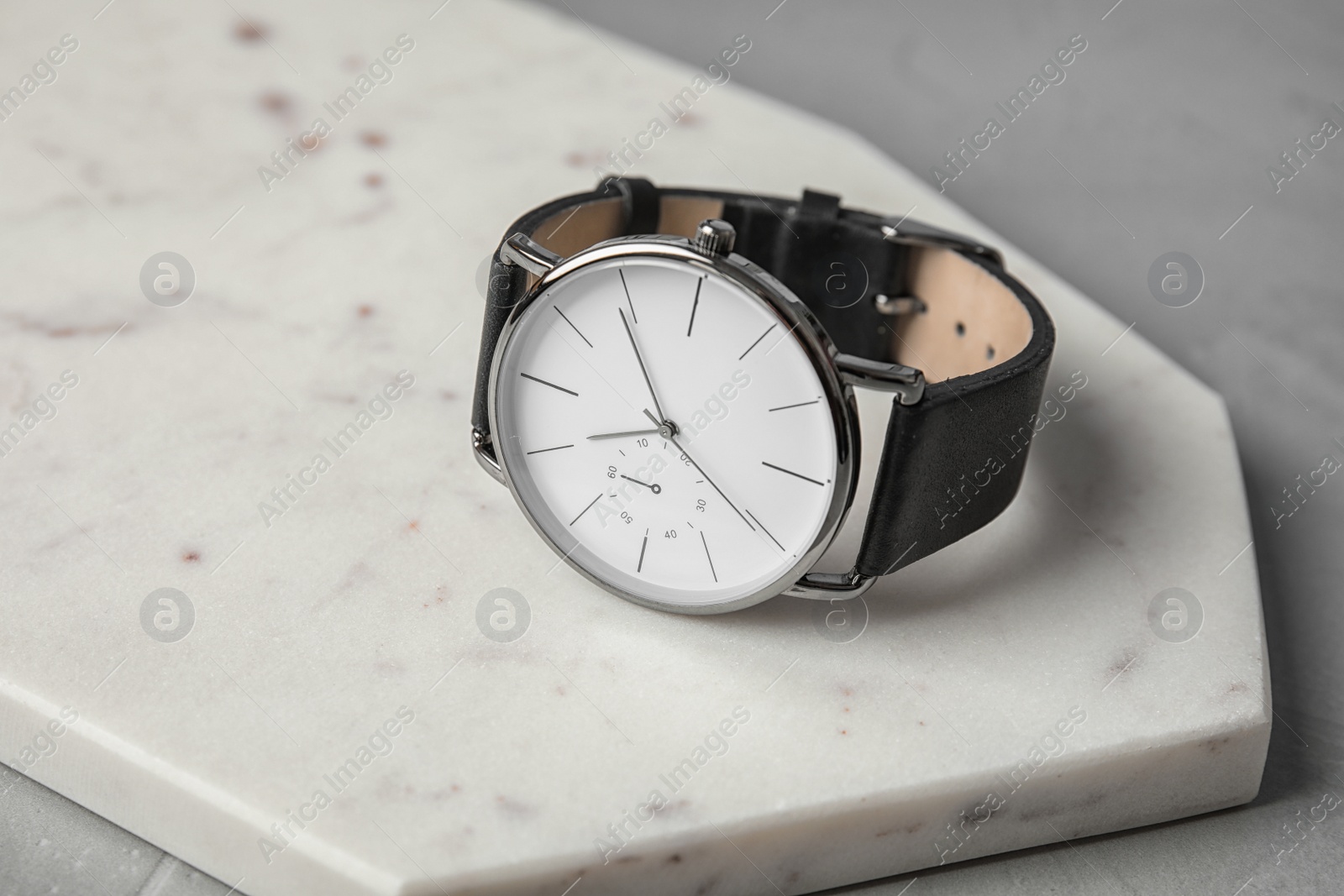Photo of Board with stylish wrist watch on gray table. Fashion accessory