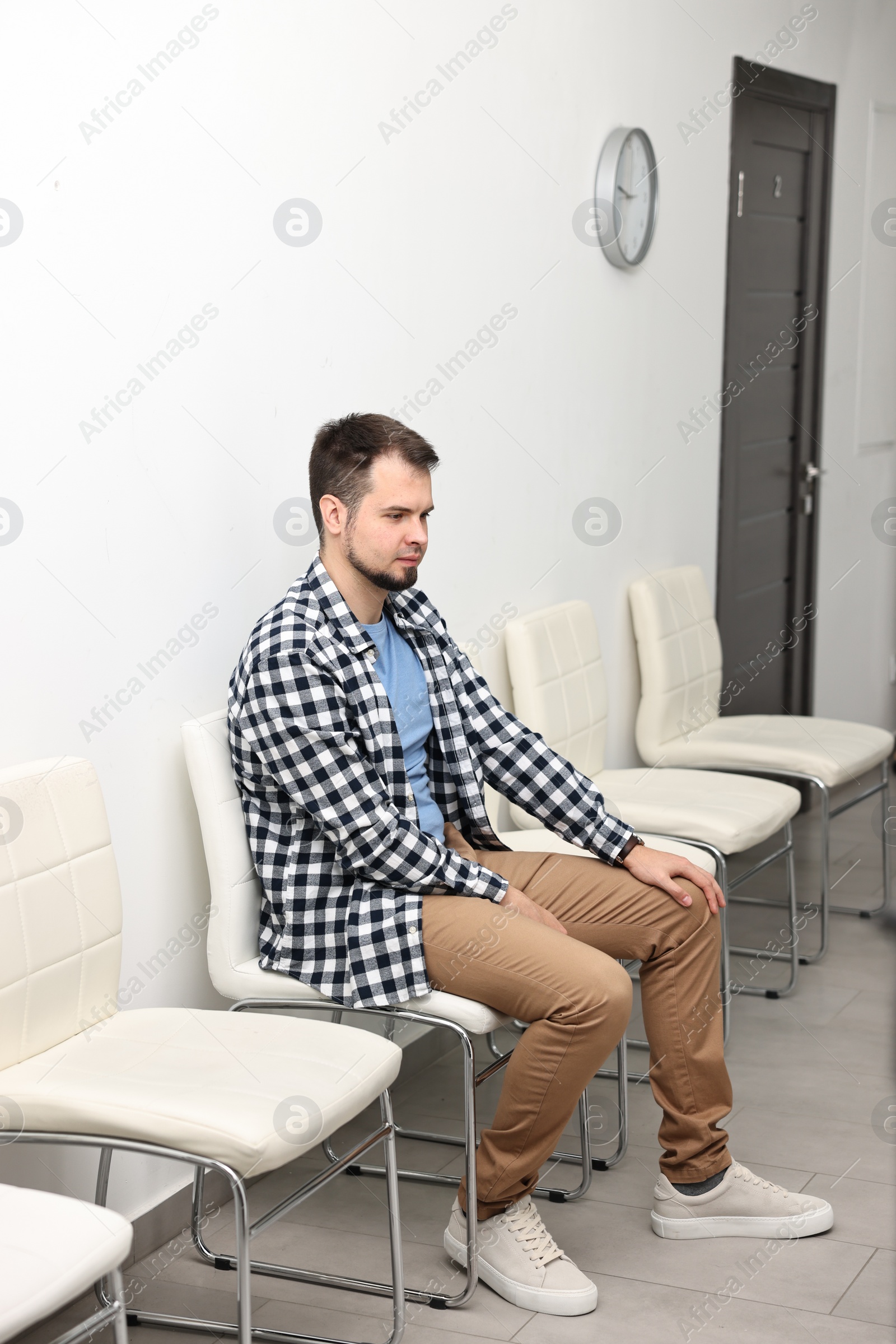 Photo of Man sitting on chair and waiting for appointment indoors