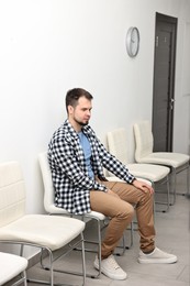 Man sitting on chair and waiting for appointment indoors