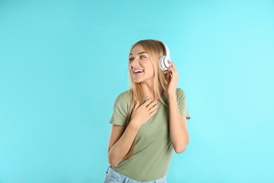 Photo of Beautiful young woman listening to music with headphones on color background
