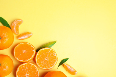 Photo of Flat lay composition with fresh ripe tangerines and leaves on light yellow background, space for text. Citrus fruit