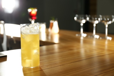 Photo of Glass of delicious cocktail with vodka on wooden counter in bar. Space for text