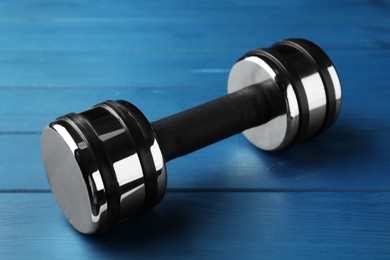 One metal dumbbell on blue wooden table