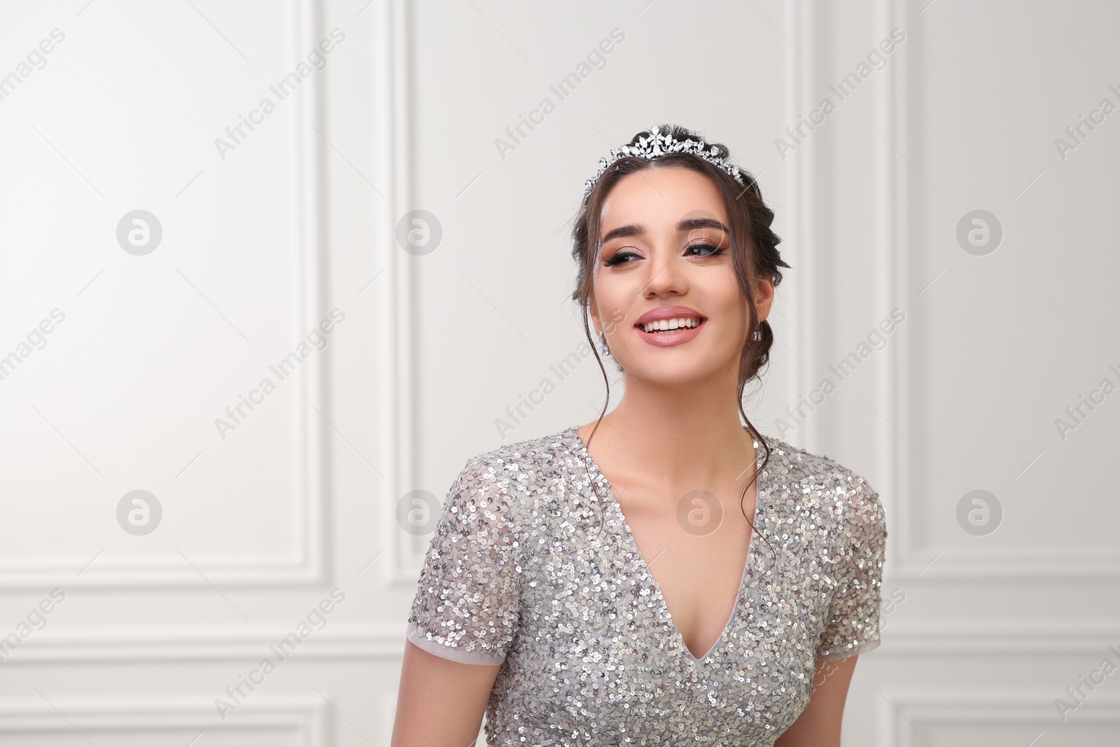 Photo of Beautiful young woman wearing luxurious tiara indoors, space for text