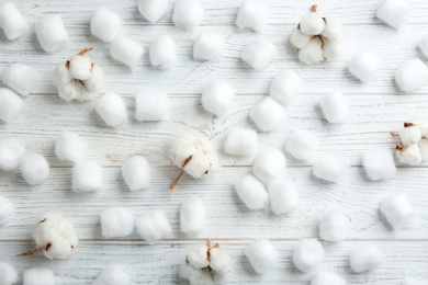 Flat lay composition with cotton balls and flowers on white wooden background