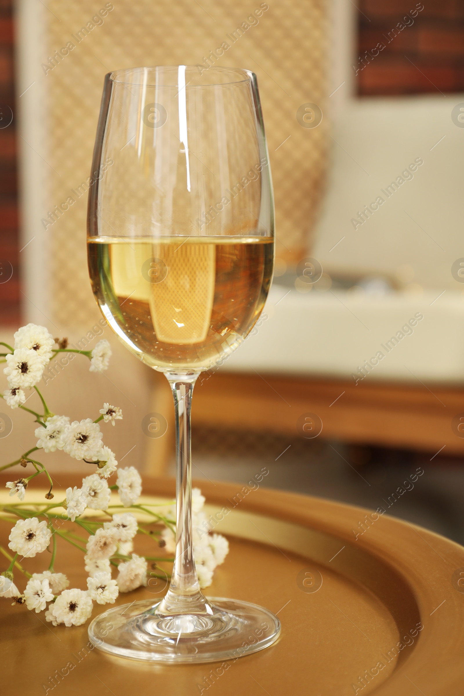 Photo of Glass of white wine and flowers on table in room. Relax at home
