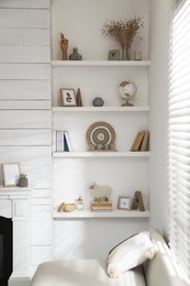Photo of Many shelves with different decor near sofa in room. Interior design