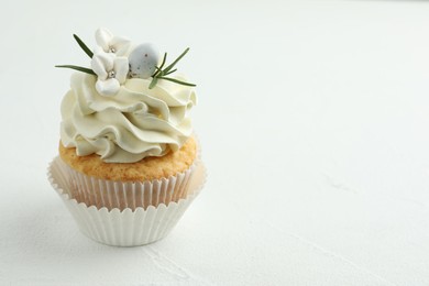 Photo of Tasty Easter cupcake with vanilla cream on white table, space for text