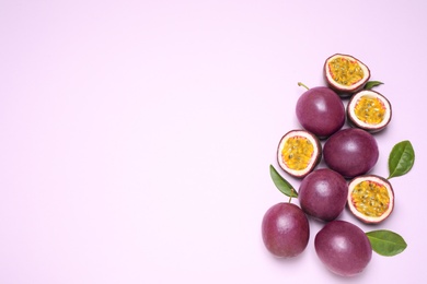 Photo of Fresh ripe passion fruits (maracuyas) with leaves on light pink background, flat lay. Space for text