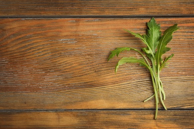 Photo of Fresh arugula on wooden table, flat lay. Space for text