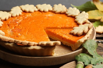 Photo of Delicious homemade pumpkin pie on wooden plate, closeup
