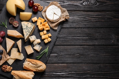 Photo of Different types of delicious cheese served on black wooden table, top view. Space for text