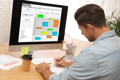 Photo of Man planning his schedule with calendar app on computer in office