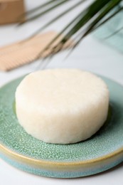 Photo of Solid shampoo bar and leaf on white table, closeup. Hair care