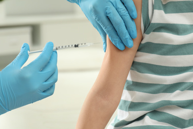 Doctor vaccinating little child in clinic, closeup