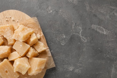 Pieces of delicious parmesan cheese on grey table, top view. Space for text