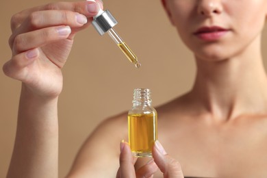 Woman with cosmetic serum in her hands on beige background, closeup