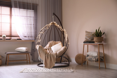 Cozy hanging chair with fairy lights in modern living room. Interior design