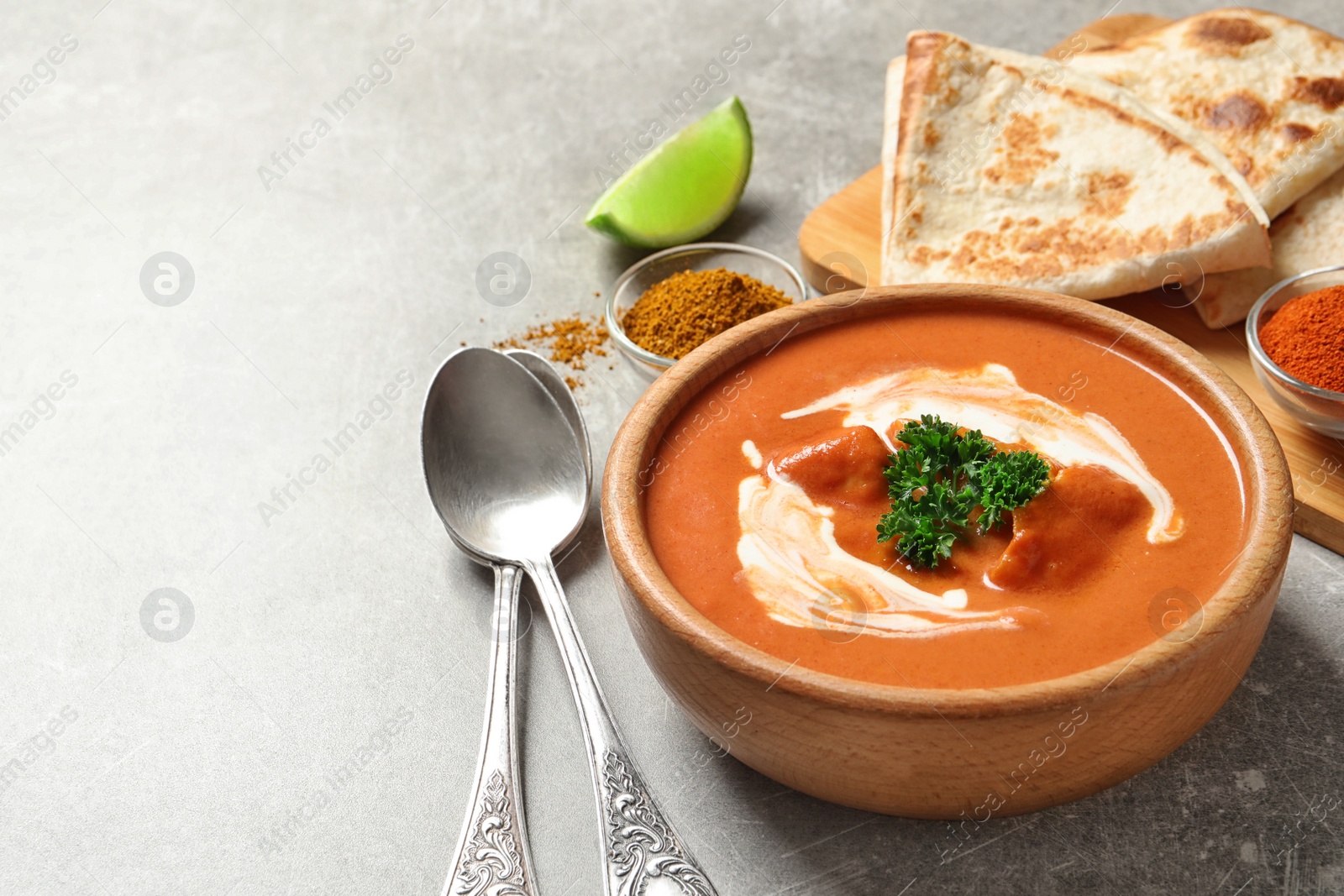 Photo of Delicious butter chicken served on grey table, space for text. Traditional indian Murgh Makhani